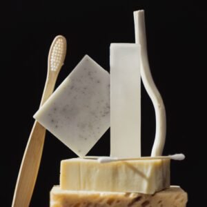 Artistic still life of soap bars, toothbrush, and cotton swabs on a black background.